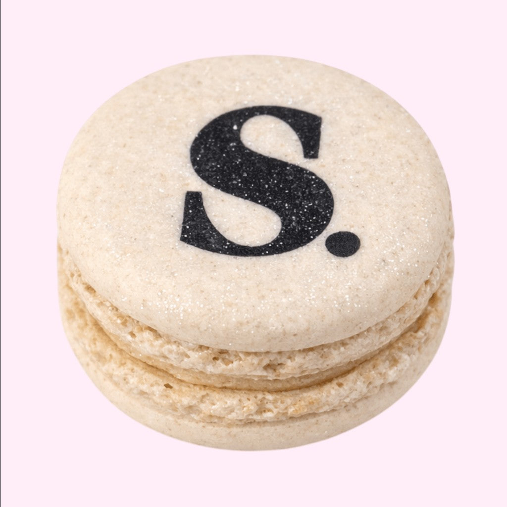 Sweet Snap Sydney beige macaron with black 'S' logo and a dot, perfect for corporate events.