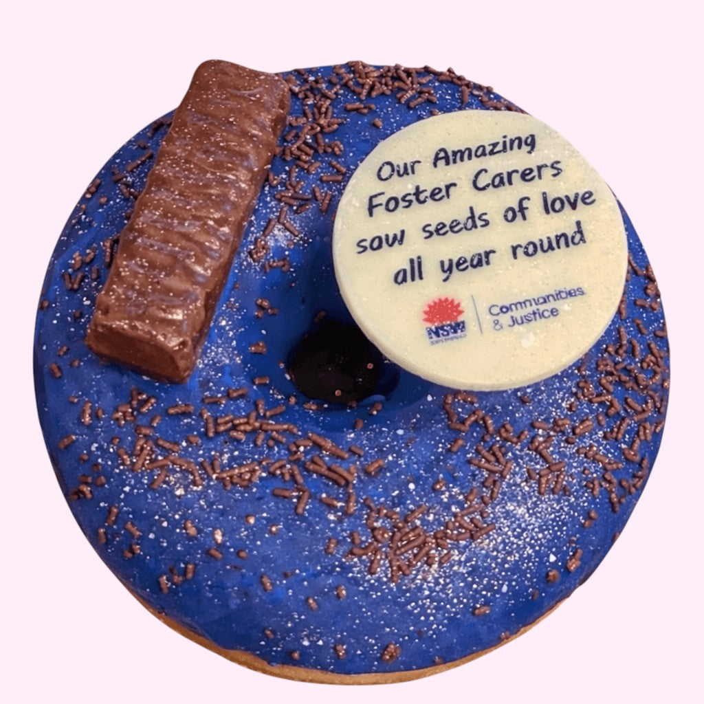 Sweet Snap Sydney blue iced donut with chocolate bar, sprinkles, and custom white chocolate disc with text and logo.