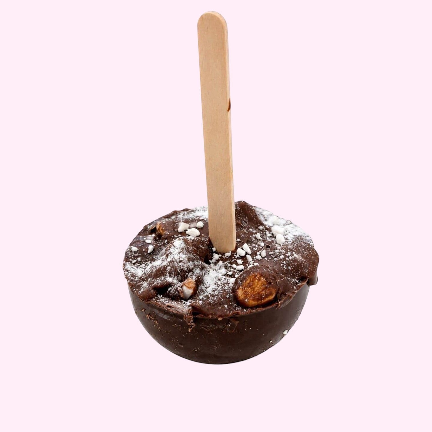 Sweet Snap Sydney dark chocolate hot chocolate bomb with nuts and powdered sugar, on a wooden stick.