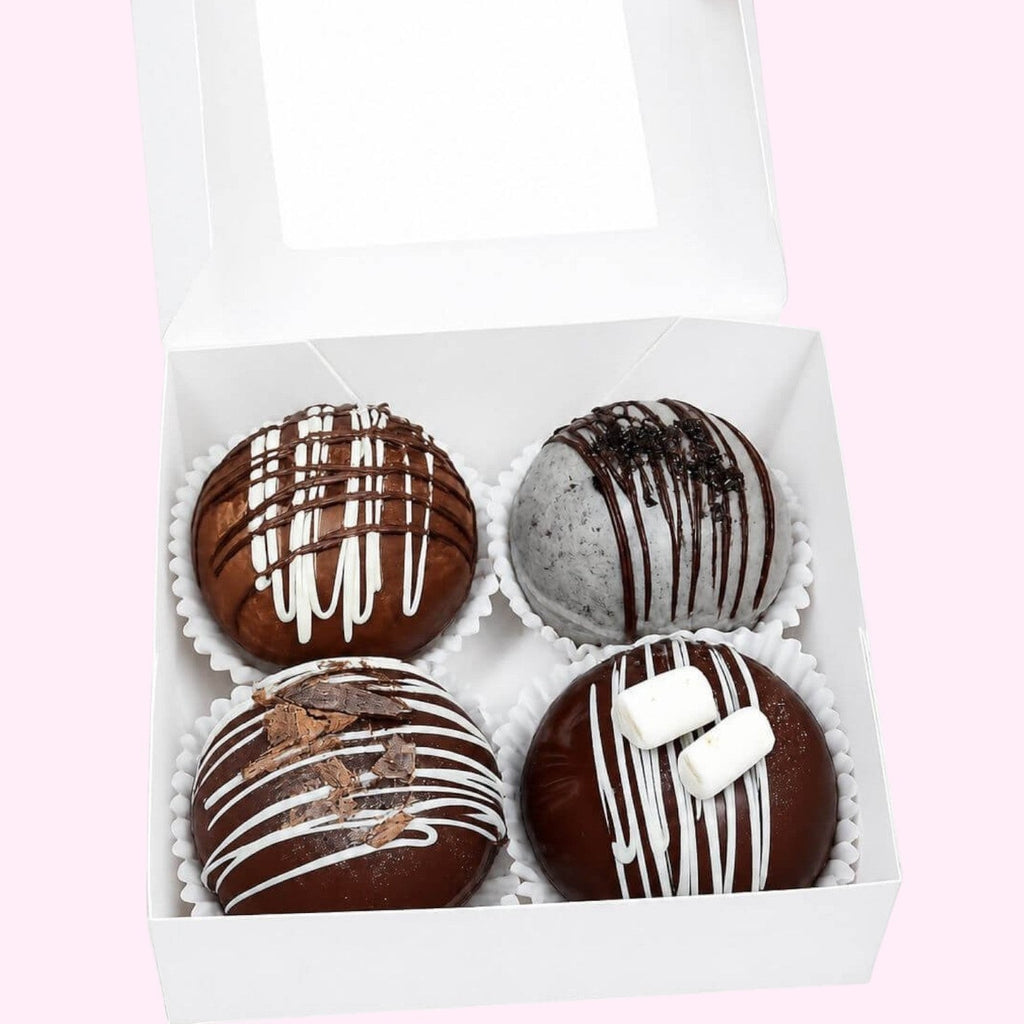 Sweet Snap Sydney hot chocolate bombs in a white box. Four bombs: chocolate with white drizzle, Oreo, chocolate with shavings, and chocolate with marshmallows.