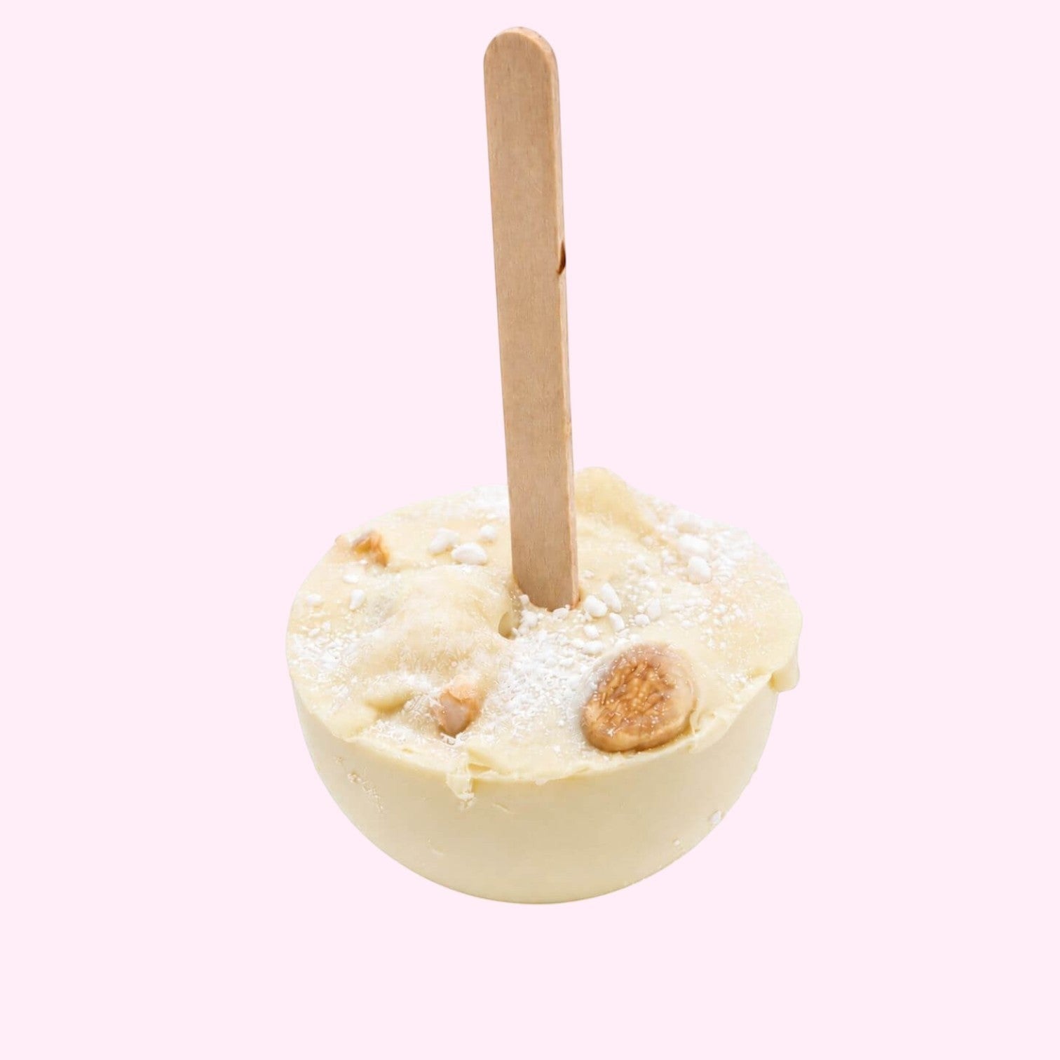 Sweet Snap Sydney white chocolate hot chocolate bomb with a wooden stick, topped with powdered sugar and nuts.
