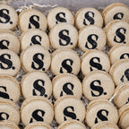 Sweet Snap Sydney beige macarons with black 'S' logo and glitter, perfect for corporate events.